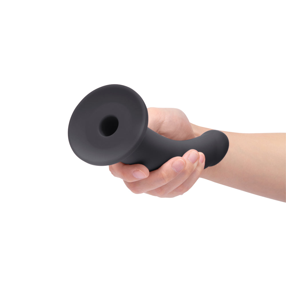 B-vibe Essentials 7 Inch Smooth Silicone Dildo Black held in a hand, showcasing its sleek design.