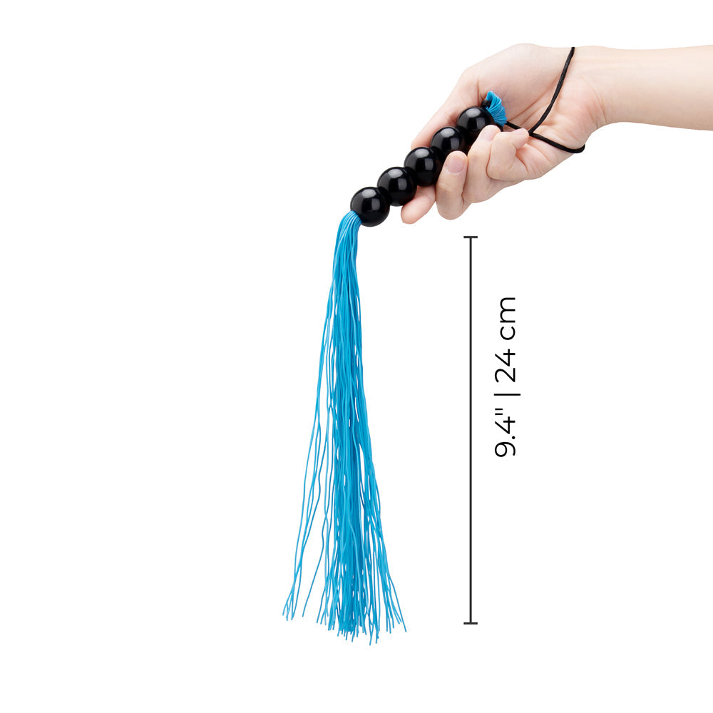 B-vibe Essentials Beaded Flogger held in hand, featuring black beads and blue tails, measuring 9.4 inches.