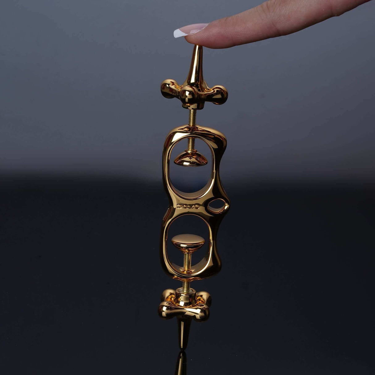 UPKO Thumb Metal Cuffs held by a hand, showcasing their sleek gold design and unique restraint mechanism.
