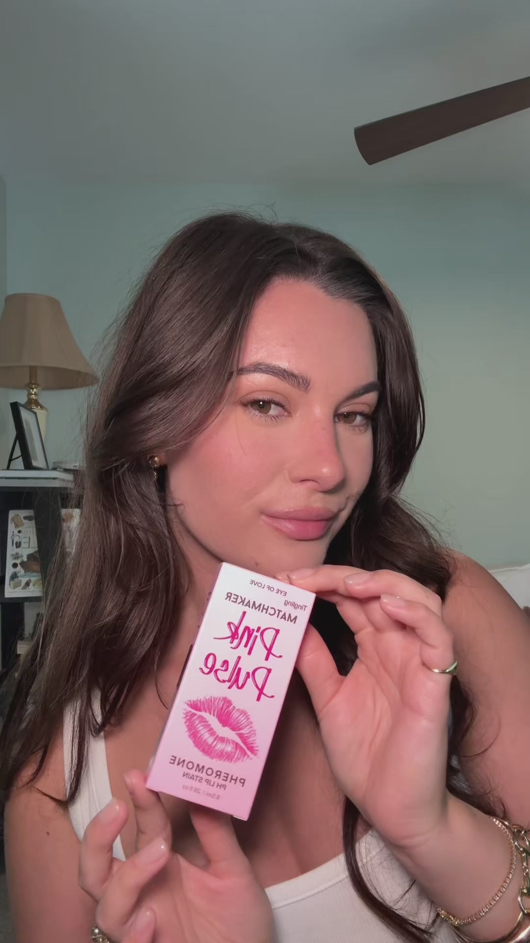 Eye Of Love Matchmaker Pink Pulse Pheromone pH Lip Stain packaging held by a woman with a soft and polished look.