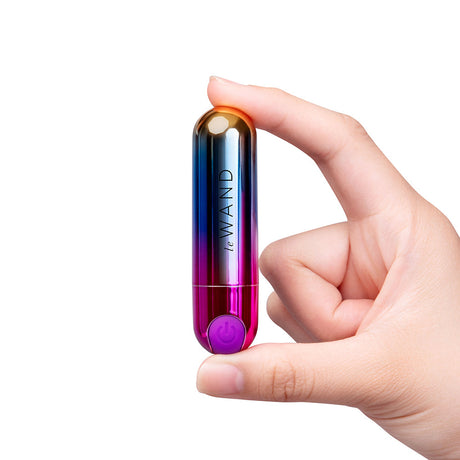 Le Wand Essentials Rechargeable Rainbow Bullet Vibrator held in hand, showcasing its sleek design and vibrant colors.
