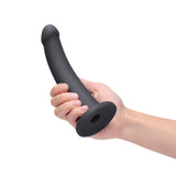 B-vibe Essentials 7 Inch Smooth Silicone Dildo Black held by a hand showcasing its sleek design and smooth surface.
