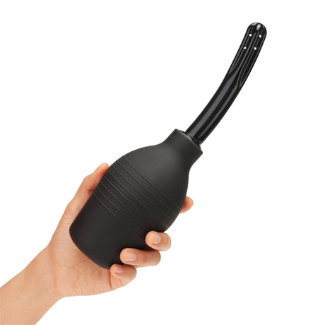 b-Vibe Essentials Enema Douche With Nozzle 310 mL Black in hand, showcasing its sleek design and comfortable grip.