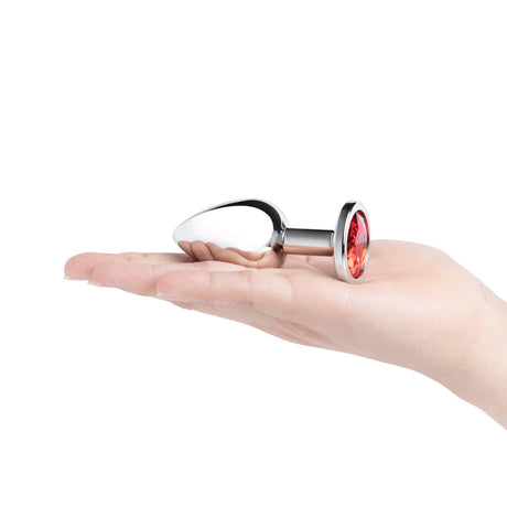 B-Vibe 3.25 Inch Stainless Steel Jewel Butt Plug Red resting in a hand, showcasing its polished elegance and red jewel base.