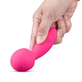 A hand holding the Together Spark On The Go Mini Wand Vibrator, showcasing its vibrant pink color and sleek design.