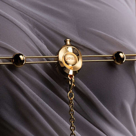 UPKO Double Bar Vibration Nipple Clamps with Clitoral Chain on mesh fabric background.