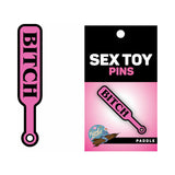 Wood Rocket Sex Toy Pin Bitch Paddle Pink is a playful enamel lapel pin featuring a bright pink paddle design.