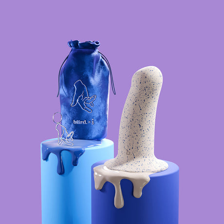 Biird Boo 5.5 Inch Silicone Suction Cup Dildo Blue displayed with storage bag on artistic blue pedestal.