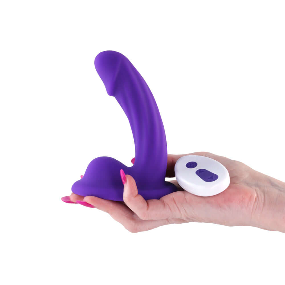 Colours Curve Vibrating 5 inch Dildo Purple held in hand with remote control for targeted stimulation.