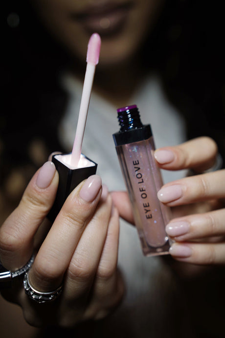 Eye Of Love Matchmaker Pink Pulse Pheromone pH Lip Stain being held with an applicator, showcasing its stylish packaging.
