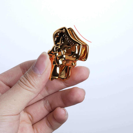 Hand holding a gold bowknot binder clip style nipple clamp showcasing its unique shell design and embossed pattern.