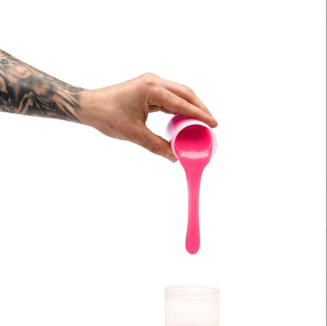 Clone-A-Willy Silicone Refill Hot Pink being poured from a cup, showcasing vibrant pink silicone.