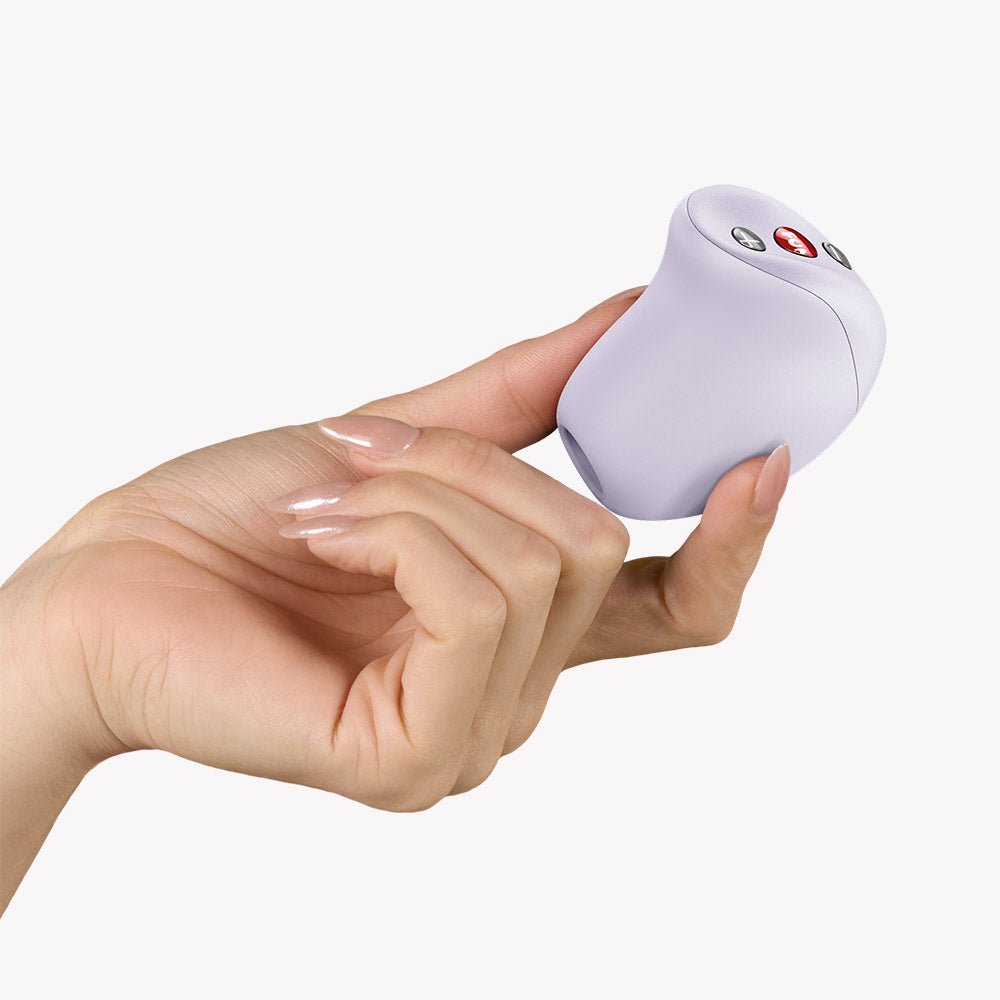 Fun Factory Mea Air Pulse Vibrator Purple being held in a hand, showcasing its ergonomic design and control buttons.