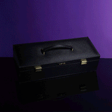Luxury black leather bondage tools case from UPKO on a reflective surface with a purple background.