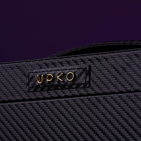Close-up of UPKO logo on luxurious black leather bondage tools case with textured design.