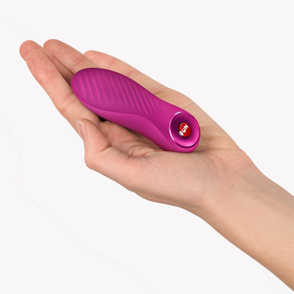 Fun Factory Bijou Bullet Vibrator Magenta in hand, showcasing its compact design and textured surface.