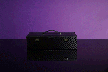 UPKO Luxury Italian leather bondage tools case with handle, reflecting on a dark surface against a purple background.