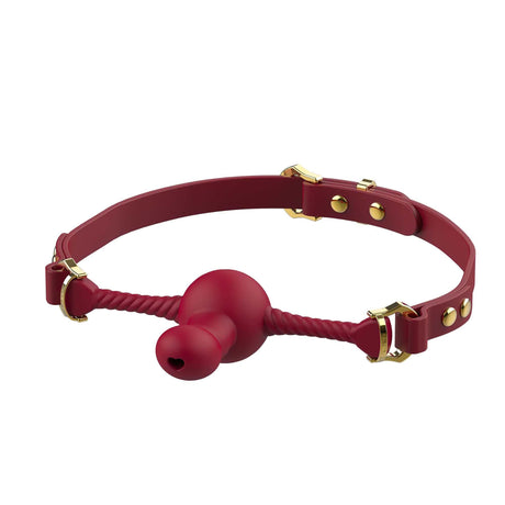 Red silicone dildo-shaped mouth gag with adjustable strap and gold hardware accents, offering luxury and control.