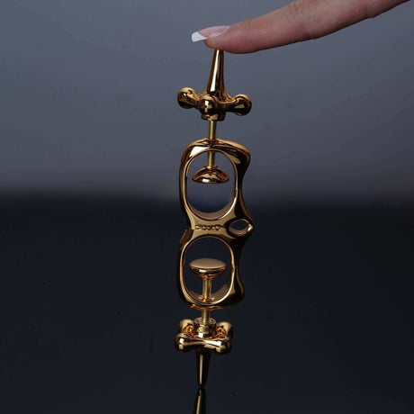 UPKO Thumb Metal Cuffs held by a hand, showcasing their sleek gold design and unique restraint mechanism.