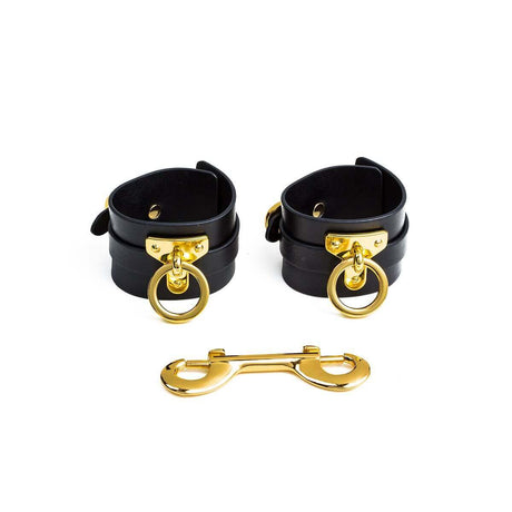 Luxury black leather wrist cuffs with golden hardware for bondage play, ideal for BDSM enthusiasts.
