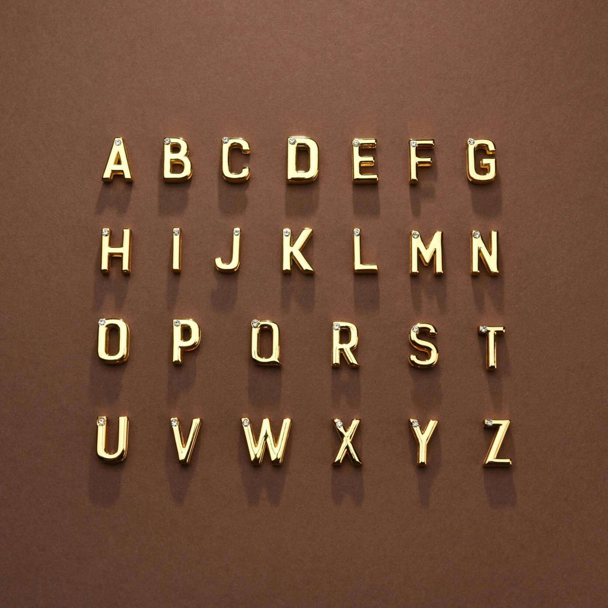 Alphabet letters A to Z in gold on a brown background, showcasing stylish typography design.