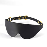 Black leather eye mask with gold hardware, part of a premium BDSM kit for enhanced sensory play.